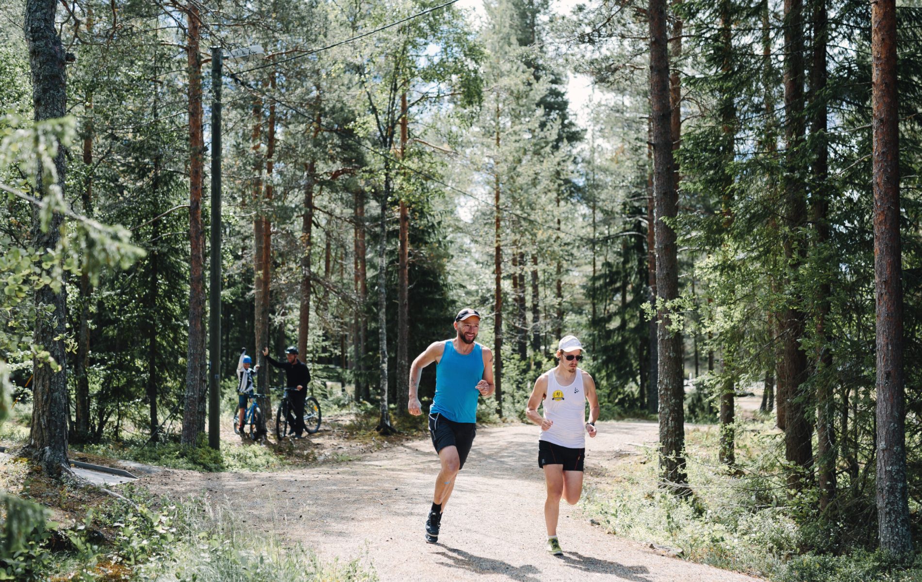 Två personer som löptränar och motionerar i skogen med cyklister i bakgrunden - stor (486487)